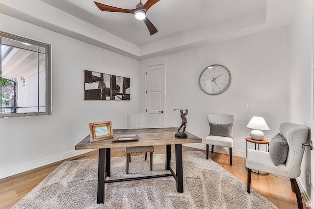 office space with ceiling fan, baseboards, a raised ceiling, and wood finished floors