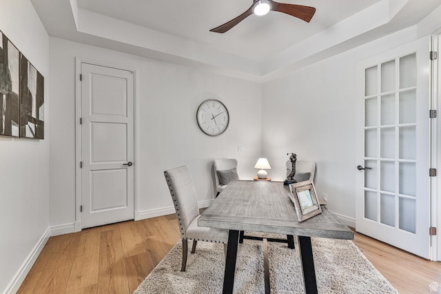 office with baseboards, a raised ceiling, a ceiling fan, and light wood-style floors