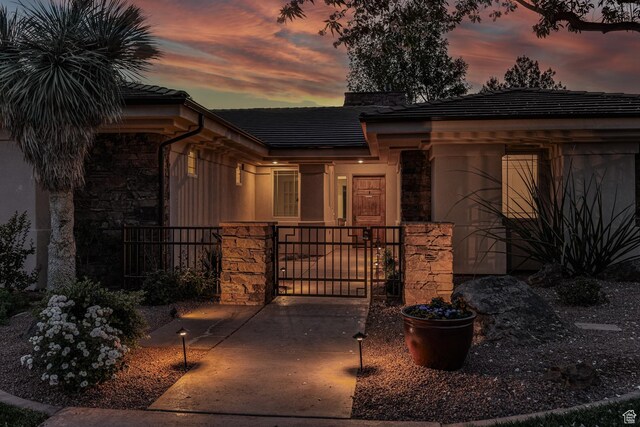 view of front of house featuring stone siding, a gate, and fence