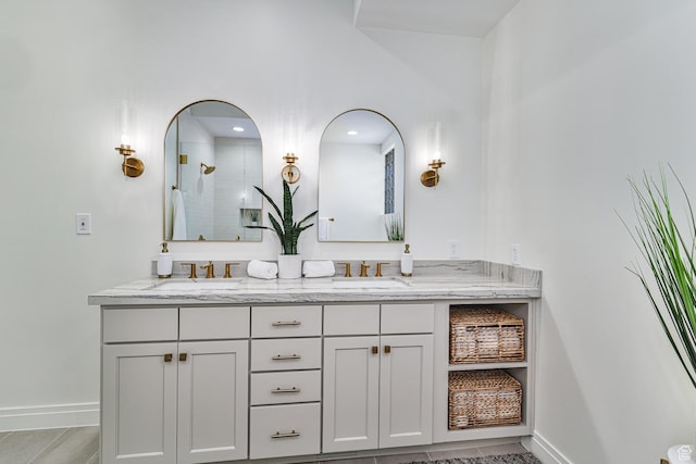 bathroom featuring a tile shower, double vanity, and a sink