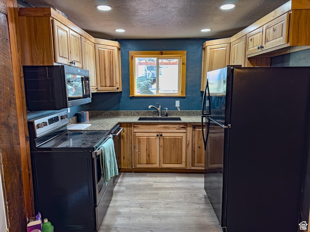 kitchen with recessed lighting, light wood-style floors, a sink, a textured ceiling, and black appliances