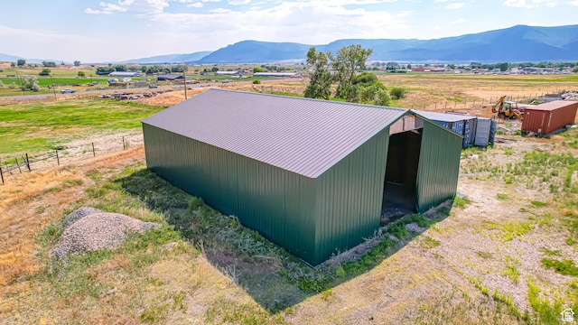 view of pole building with fence, a mountain view, and a rural view