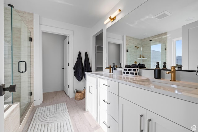 2452 W 2950 N Unit 112, Farr West, UT 84404 - bathroom with double vanity, wood finished floors, a stall shower, and a sink