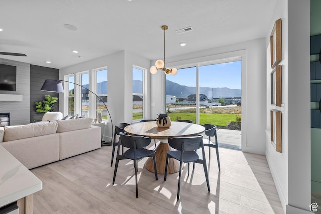 2452 W 2950 N Unit 112, Farr West, UT 84404 - dining space featuring a large fireplace, visible vents, light wood-style flooring, a mountain view, and recessed lighting
