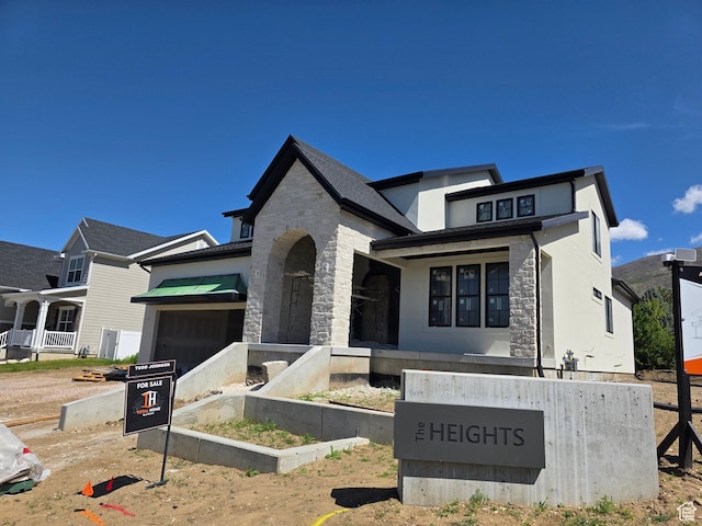 french country home featuring a garage, stucco siding, and stone siding