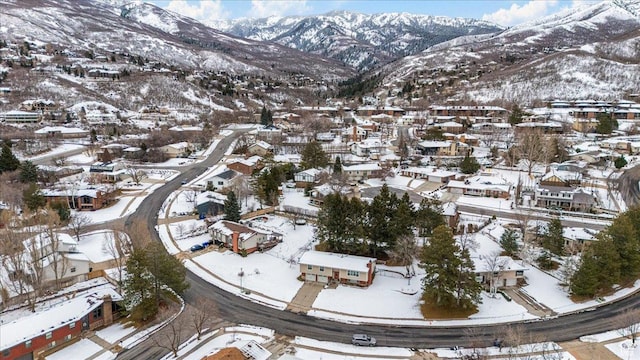 snowy aerial view with a mountain view and a residential view