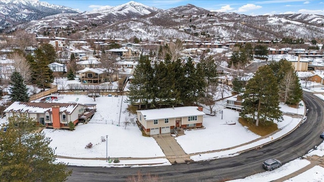 snowy aerial view with a mountain view and a residential view