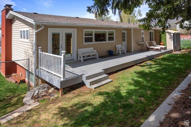 rear view of house with a chimney, french doors, a wooden deck, and a lawn