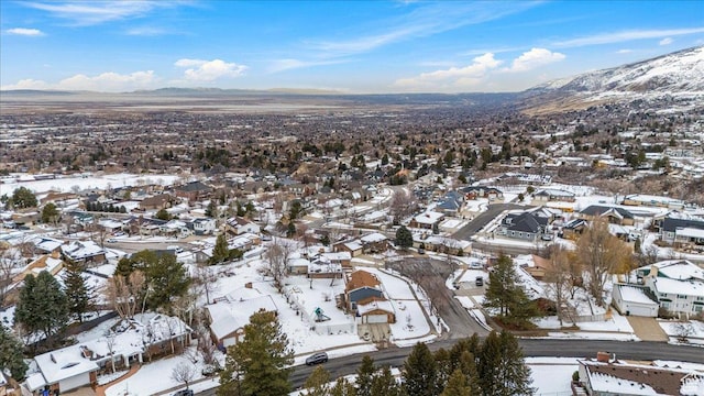 snowy aerial view featuring a mountain view and a residential view