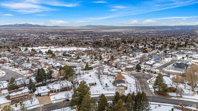 snowy aerial view featuring a mountain view and a residential view