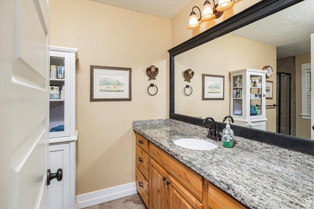 bathroom with vanity, a textured ceiling, and baseboards