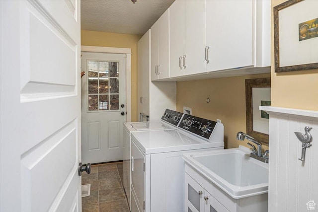 laundry room with dark tile patterned flooring, a textured ceiling, a sink, cabinet space, and washer and clothes dryer