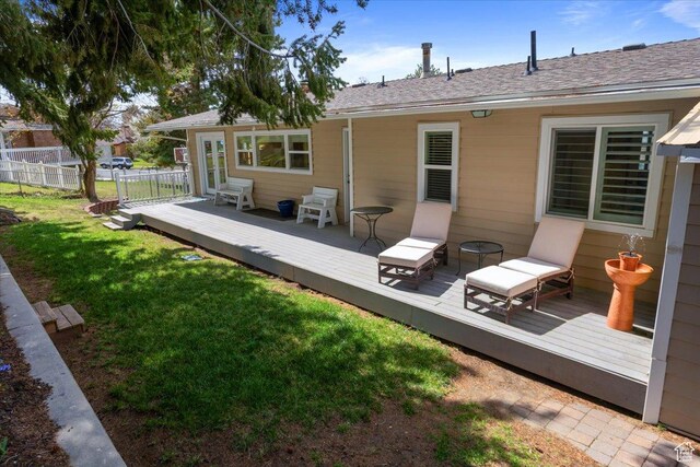 rear view of property featuring a yard, a wooden deck, and fence