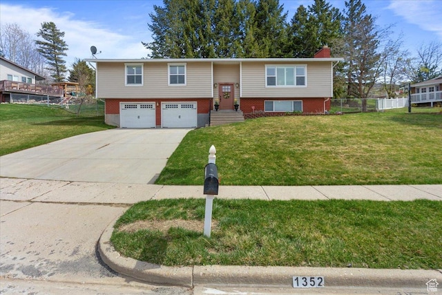 split foyer home featuring a garage, concrete driveway, fence, and a front lawn