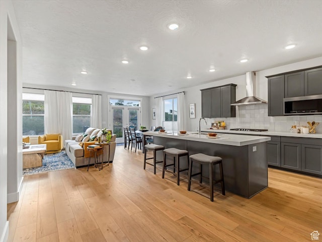14678 S Silver Blossom Way E, Draper, UT 84020 - kitchen featuring wall chimney range hood, gas stovetop, stainless steel microwave, open floor plan, and an island with sink
