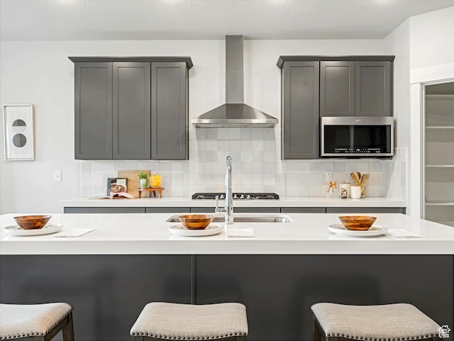 14678 S Silver Blossom Way E, Draper, UT 84020 - kitchen with wall chimney range hood, stainless steel microwave, tasteful backsplash, light countertops, and a kitchen bar