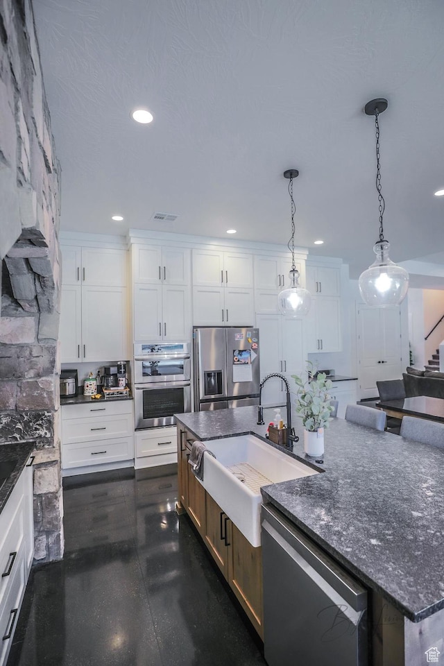 2906 N Purple Sage Rd, Apple Valley, UT 84737 - kitchen with stainless steel appliances, a sink, white cabinetry, a kitchen island with sink, and pendant lighting