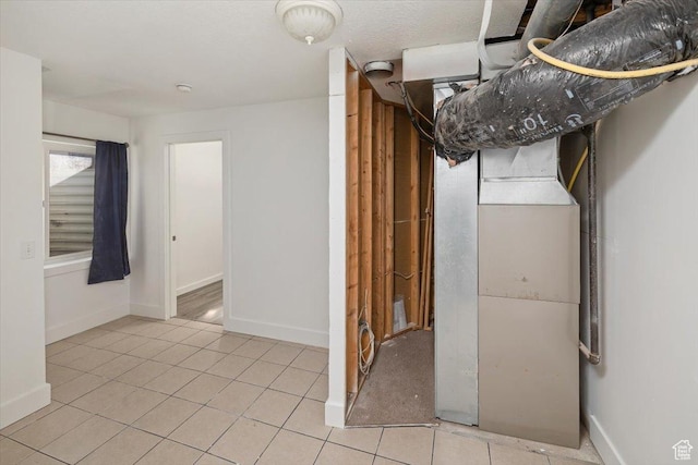 basement featuring light tile patterned floors and baseboards
