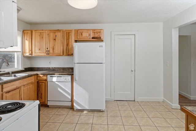 kitchen with white appliances, light tile patterned flooring, a sink, a textured ceiling, and dark countertops