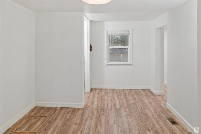 unfurnished room featuring light wood-style flooring, baseboards, and visible vents