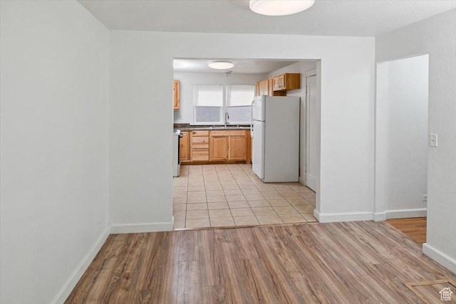 kitchen featuring baseboards, dark countertops, light wood-style flooring, and freestanding refrigerator