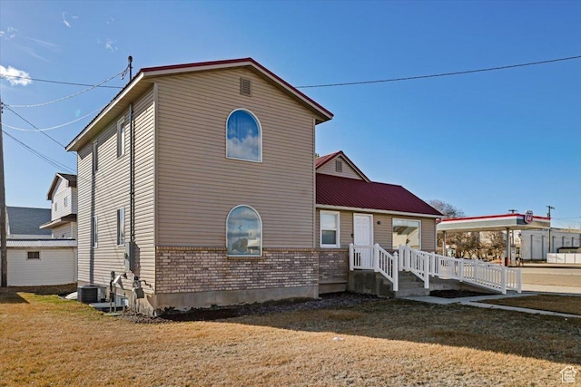 view of front of home with a front yard, cooling unit, and brick siding