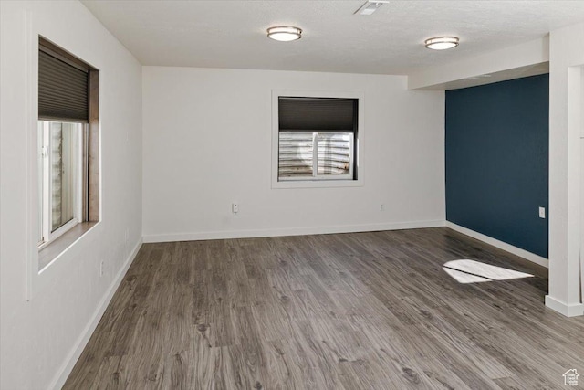 unfurnished room featuring visible vents, baseboards, a textured ceiling, and wood finished floors