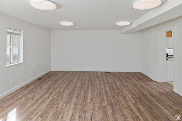 spare room featuring visible vents, a textured ceiling, baseboards, and wood finished floors