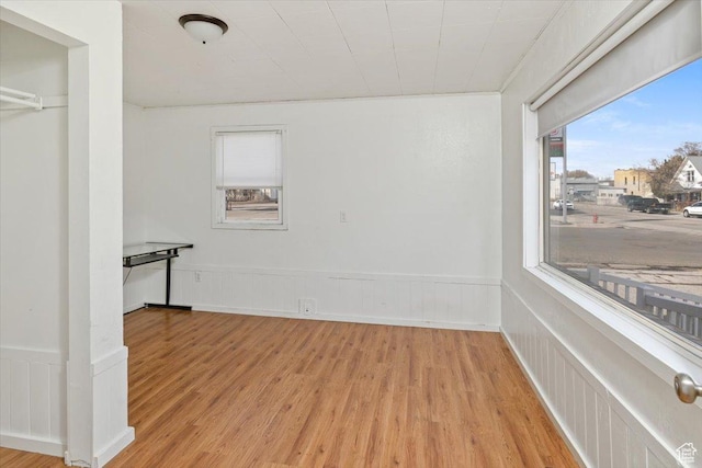 unfurnished room featuring a wainscoted wall and light wood finished floors