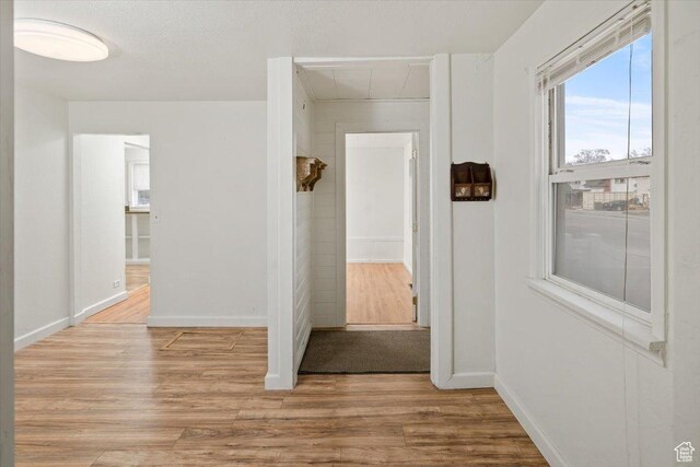 corridor featuring light wood-type flooring and baseboards