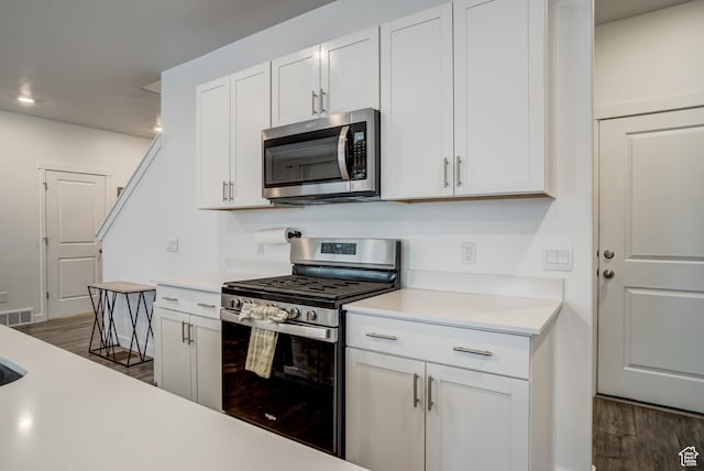 kitchen featuring visible vents, wood finished floors, light countertops, white cabinets, and stainless steel appliances