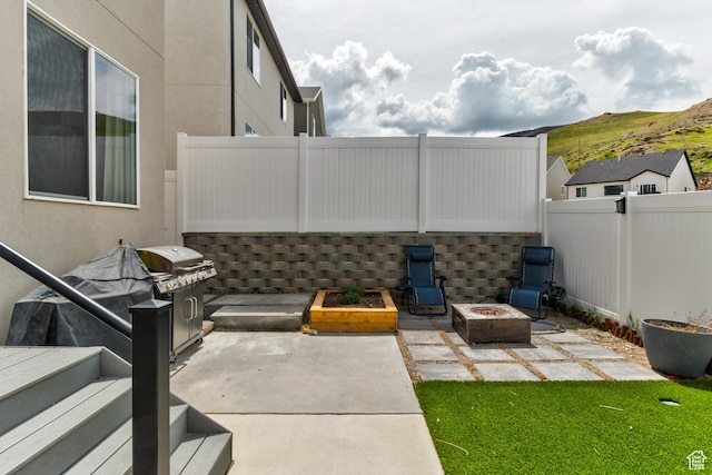 view of patio / terrace featuring a fenced backyard, an outdoor fire pit, and a mountain view