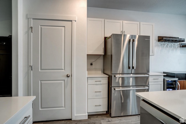 kitchen featuring freestanding refrigerator, white cabinetry, wine cooler, and light countertops