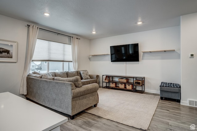 living area with recessed lighting, baseboards, visible vents, and wood finished floors