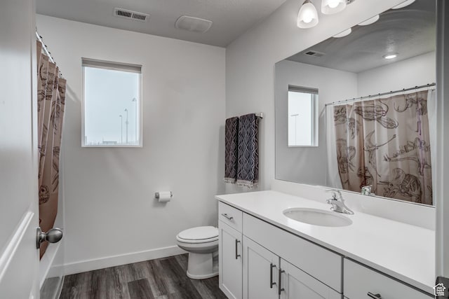 bathroom featuring vanity, toilet, baseboards, wood finished floors, and visible vents