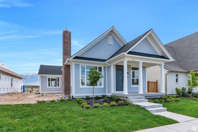 481 S Main St Unit 139, Vineyard, UT 84058 - view of front facade with a chimney, a porch, a front lawn, and a shingled roof