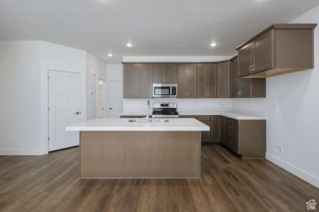 1753 W 160 S Unit 45, Pleasant Grove, UT 84062 - kitchen featuring dark brown cabinets, dark wood-type flooring, light countertops, appliances with stainless steel finishes, and a kitchen island with sink