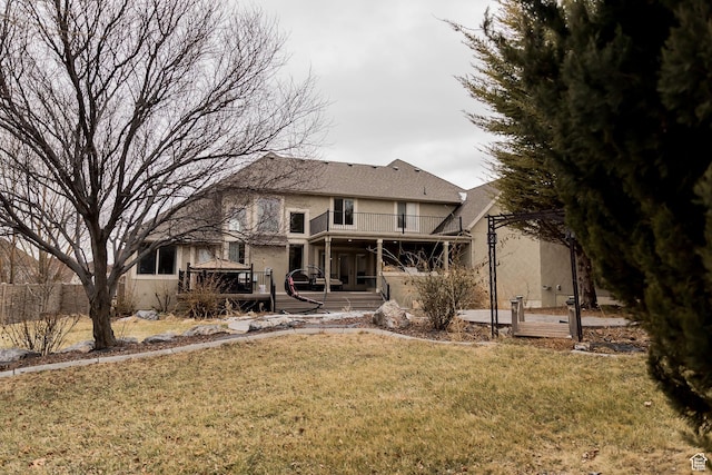 back of property featuring a yard, a wooden deck, a balcony, and stucco siding