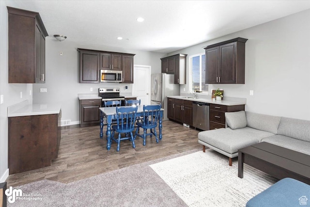 5402 W Mammoth Peak Pl, Herriman, UT 84096 - kitchen with stainless steel appliances, a sink, dark brown cabinetry, light countertops, and recessed lighting