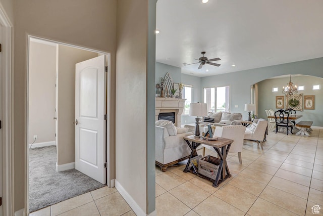 1163 W Sunrise Cir, Washington, UT 84780 - living area with arched walkways, light tile patterned floors, ceiling fan with notable chandelier, baseboards, and a glass covered fireplace