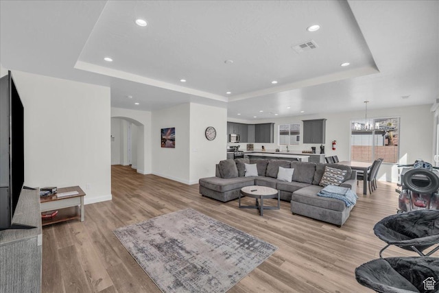 1466 N Arena Roja Dr, Washington, UT 84780 - living room featuring light wood-style flooring, visible vents, a raised ceiling, and arched walkways