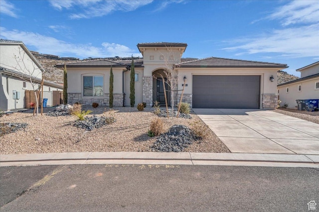mediterranean / spanish-style home featuring a garage, stone siding, driveway, and stucco siding