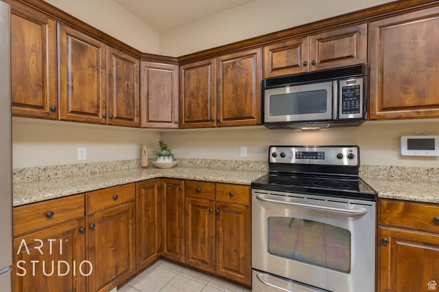 1109 N Ventana Dr, Washington, UT 84780 - kitchen with light tile patterned floors, appliances with stainless steel finishes, brown cabinetry, and light stone countertops
