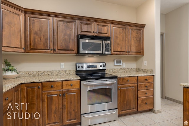 1109 N Ventana Dr, Washington, UT 84780 - kitchen with stainless steel appliances, brown cabinets, light stone counters, and light tile patterned floors