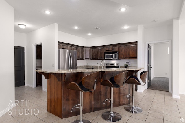 1109 N Ventana Dr, Washington, UT 84780 - kitchen featuring stainless steel appliances, a breakfast bar, an island with sink, and light stone countertops