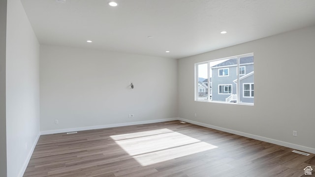 unfurnished room with light wood-type flooring, baseboards, and recessed lighting