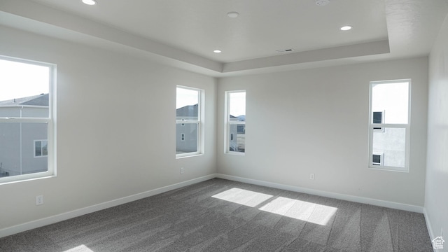 empty room with recessed lighting, visible vents, baseboards, dark colored carpet, and a raised ceiling