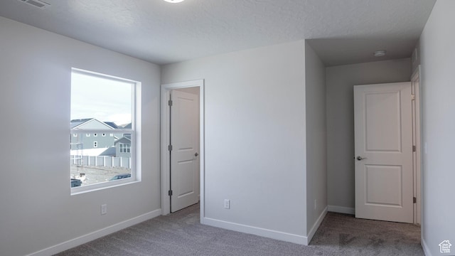 unfurnished bedroom featuring baseboards, a textured ceiling, and light colored carpet