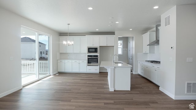 kitchen featuring stainless steel appliances, visible vents, light countertops, wall chimney exhaust hood, and decorative light fixtures