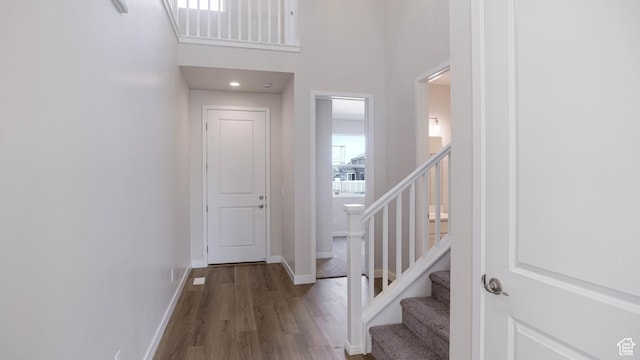 entrance foyer with stairs, dark wood-style flooring, a towering ceiling, and baseboards